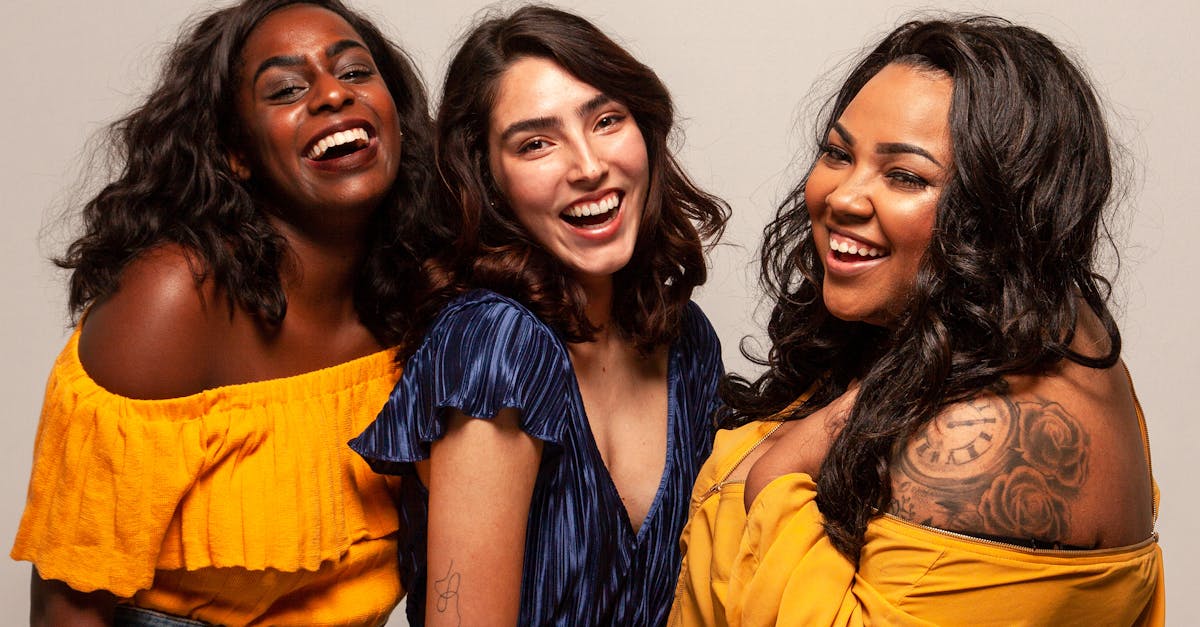 Joyful group of diverse women laughing together in bright outfits.